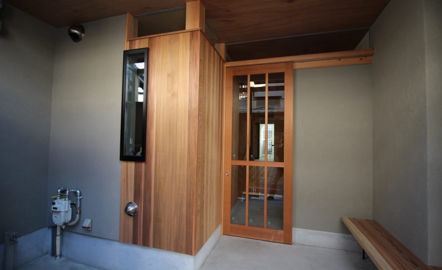 無垢材の壁とガラス入りの木製建具引き戸の玄関